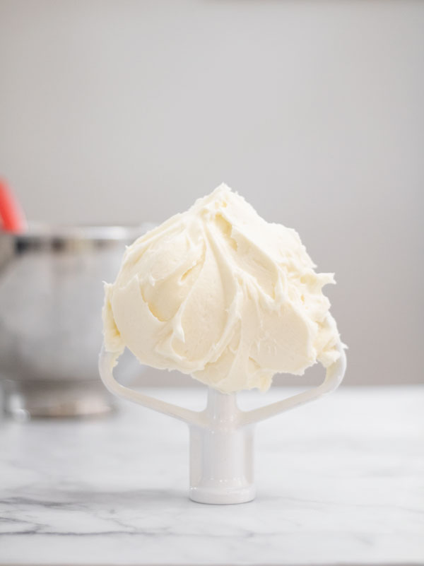 Cream cheese buttercream on paddle attachment in front of mixing bowl