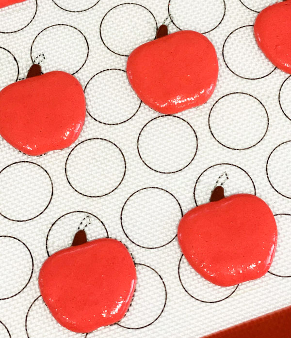 red apple shaped macarons on silicone baking mat