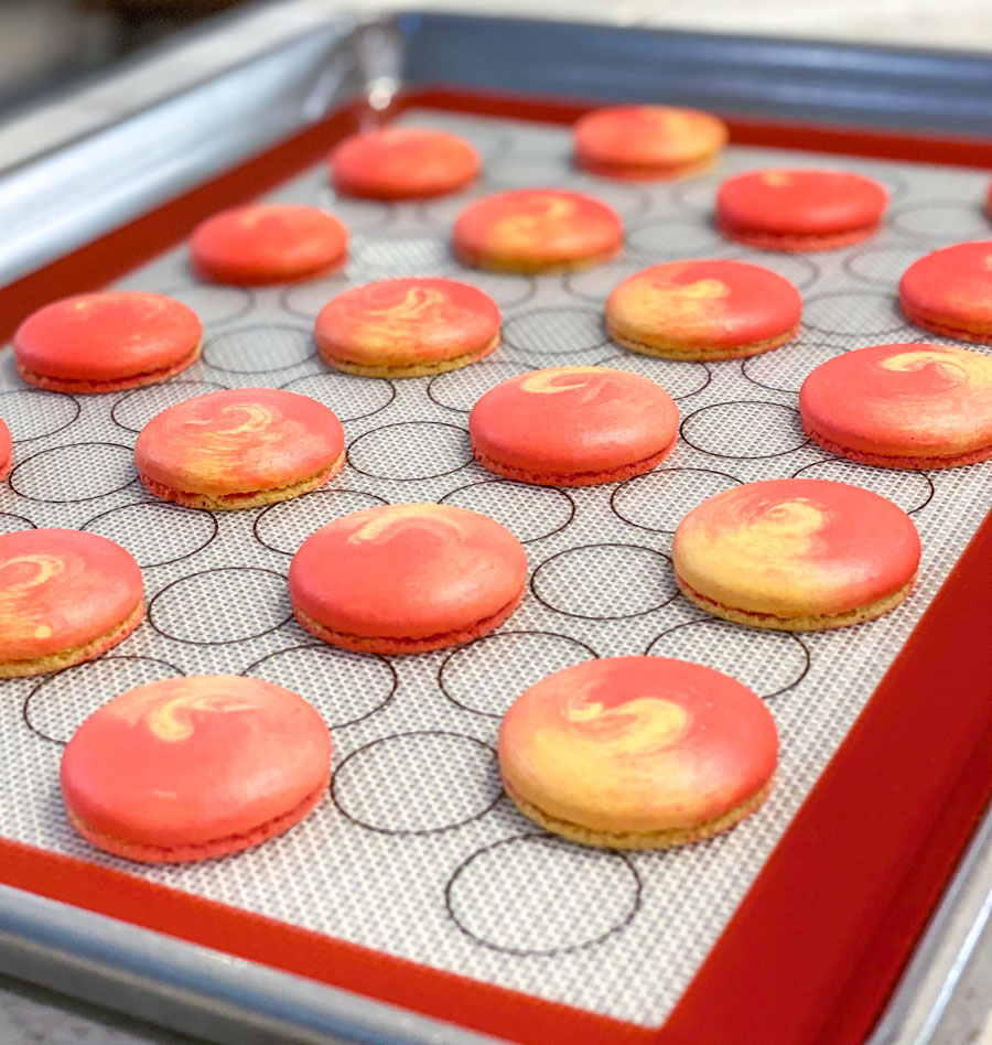 red and yellow swirled mango macarons on baking mat