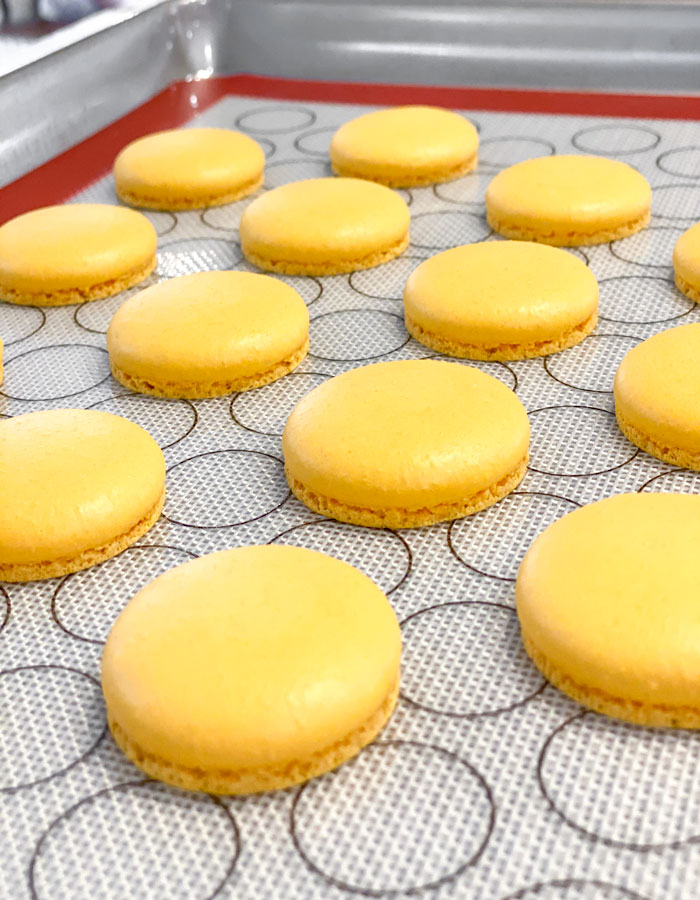 baked yellow macaron shells on baking mat