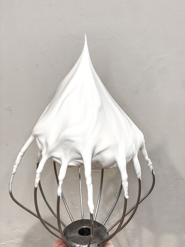 whisk with white stiff peak meringue