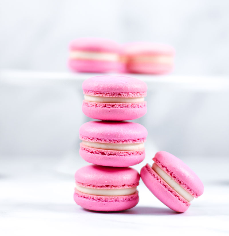 stack of pink vanilla macarons in front of white cakestand