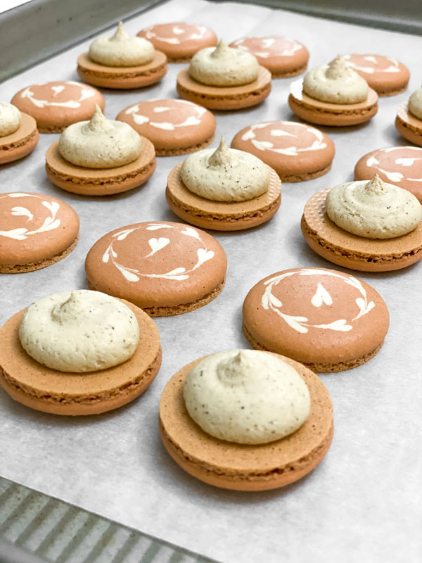 coffee macaron shells with coffee buttercream on baking tray