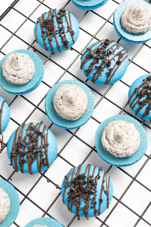 blue oreo macarons with chocolate drizzle on wire rack