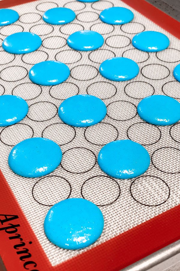 blue piped oreo macaron shells on silicone mat