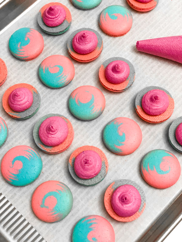 blue and pink cotton candy macarons with pink buttercream on baking tray
