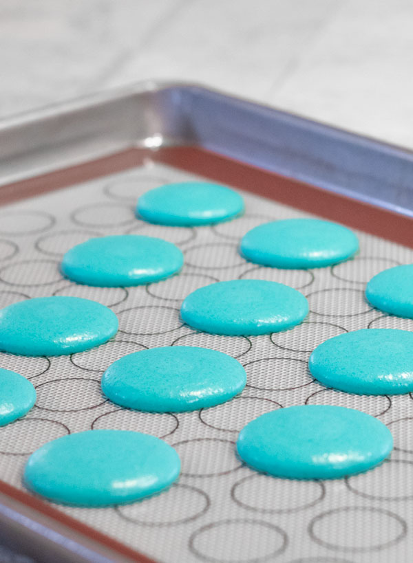 unbaked turquoise macaron shells on baking tray