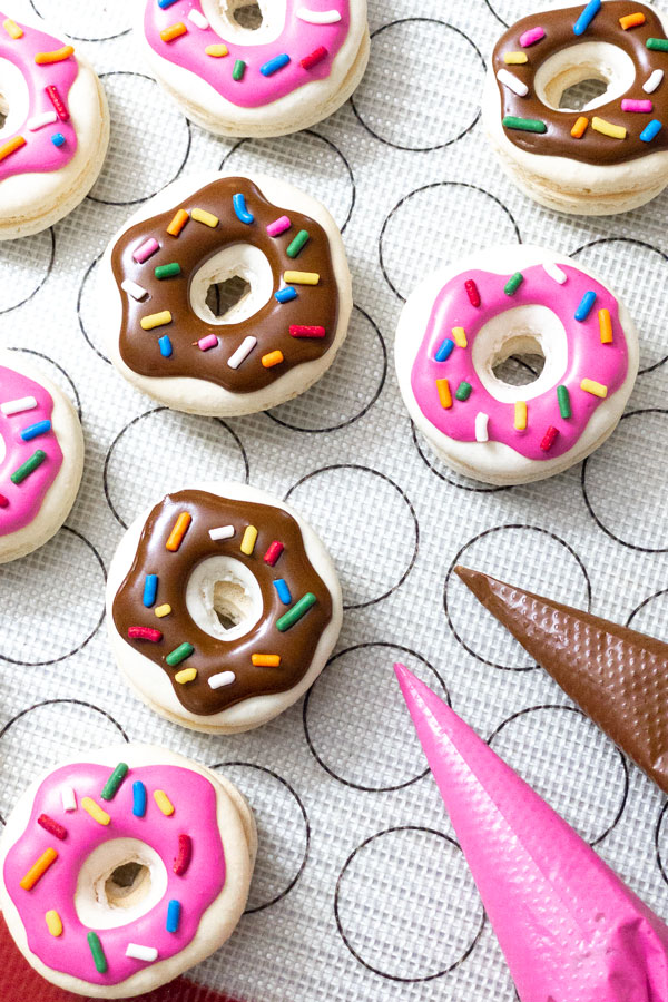 donut macarons with pink and brown decorations and sprinkles