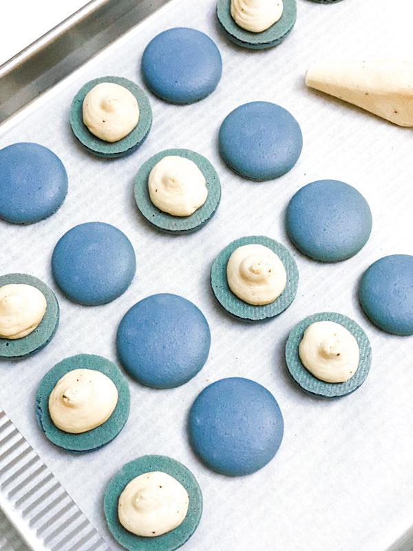 blue macaron shells with earl grey buttercream on parchment paper