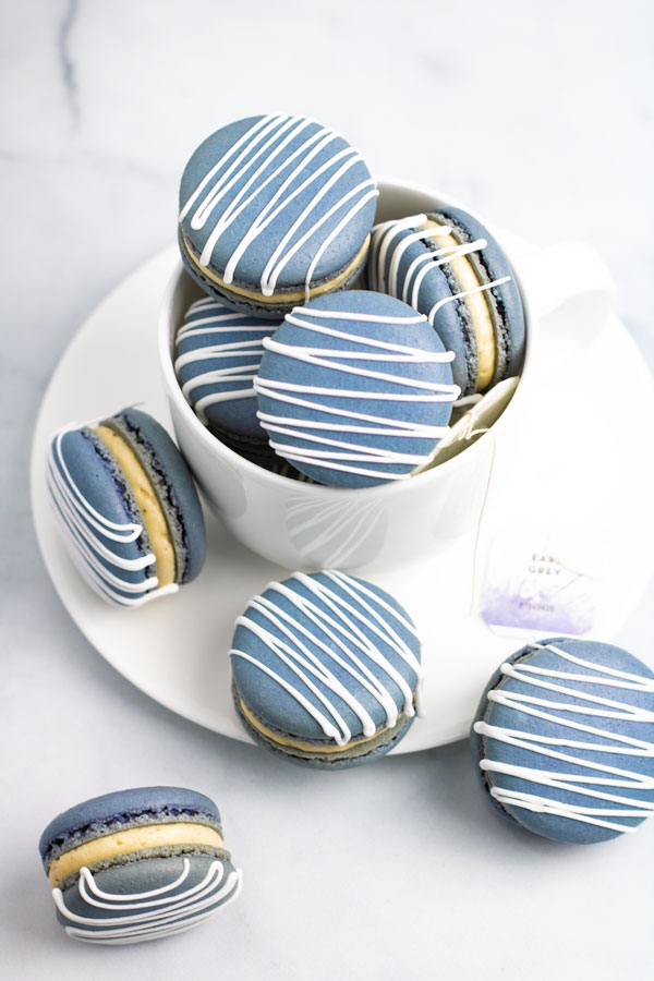 blue earl grey macarons with white drizzle inside white teacup