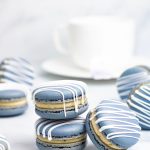 blue earl grey macarons with white drizzle in front of white teacup