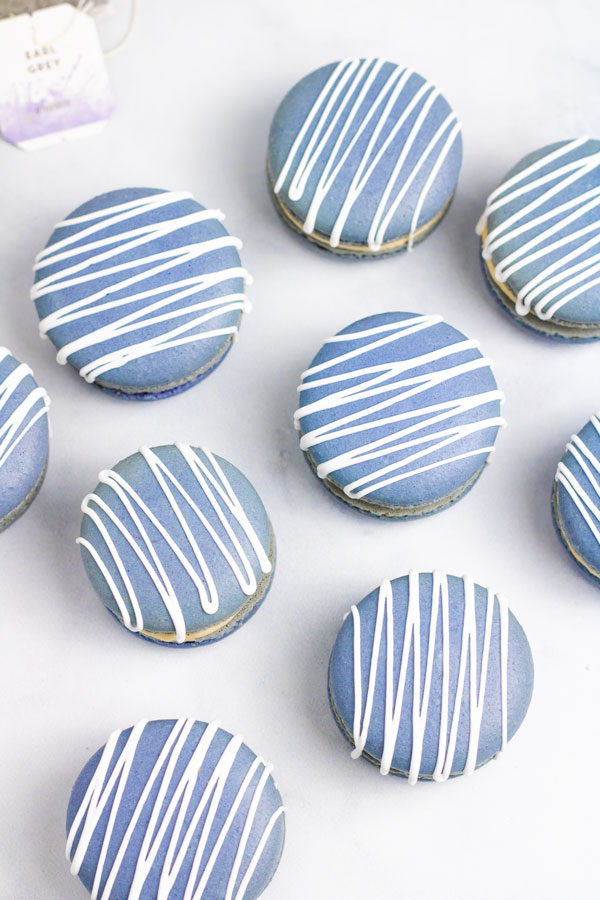 blue earl grey macarons with white drizzle on white background