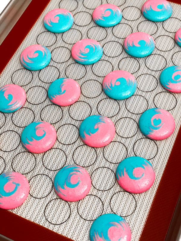 blue and pink cotton candy macaron shells on silicone mat