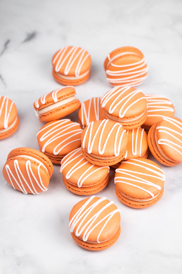 Orange pumpkin spice macarons with white drizzle