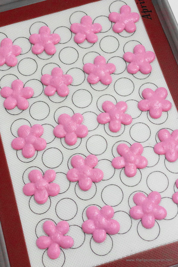 pink flower shaped macarons on silicone mat