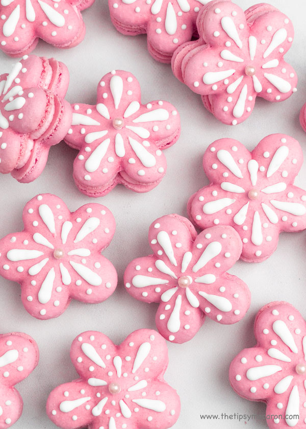 pink flower shaped macarons with white icing decorations