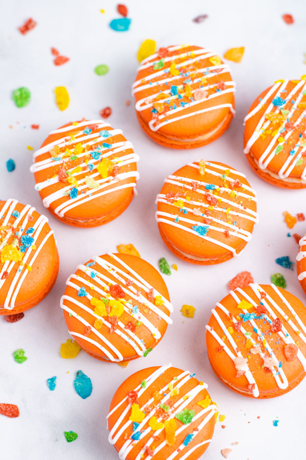 orange fruity pebbles macarons with white drizzle and cereal sprinkles