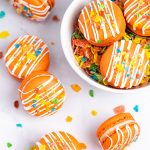 orange fruity pebbles macarons with cereal sprinkles inside cereal bowl with spoon