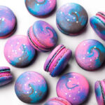 galaxy macarons with pink buttercream on white background