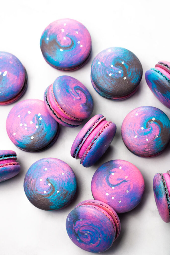 galaxy macarons with pink buttercream on white background