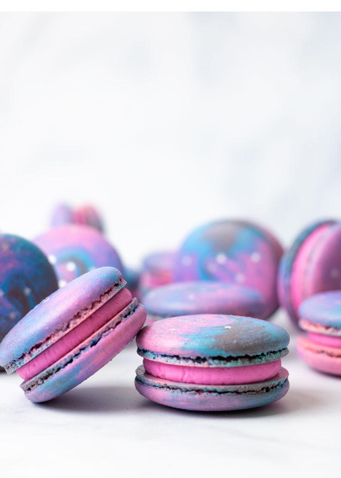 galaxy macarons with pink buttercream in front of white background