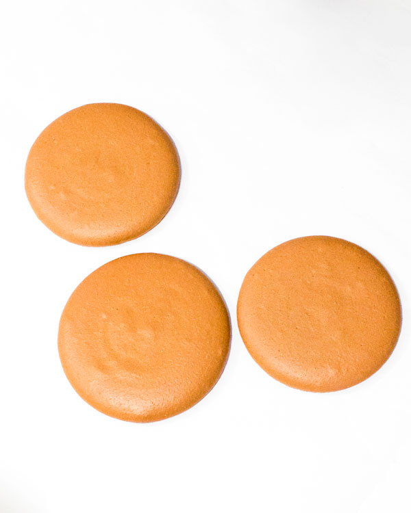 three large brown macaron shells for macaron cake