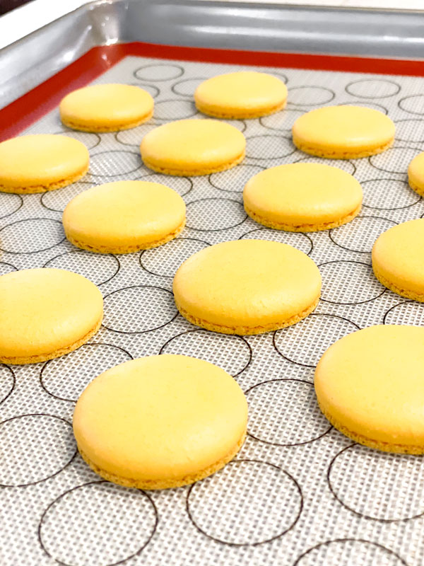 yellow macaron shells on baking mat