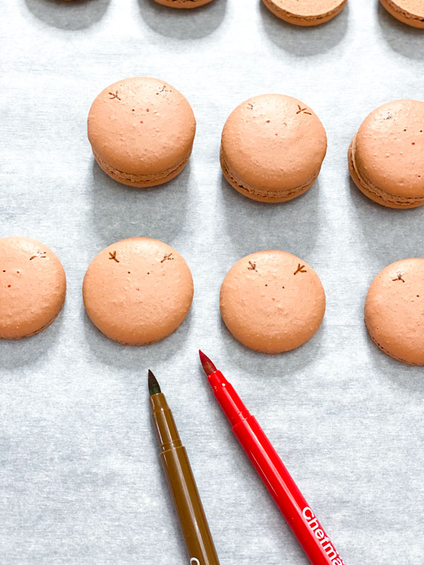 decorating reindeer macaron shells with food coloring markers