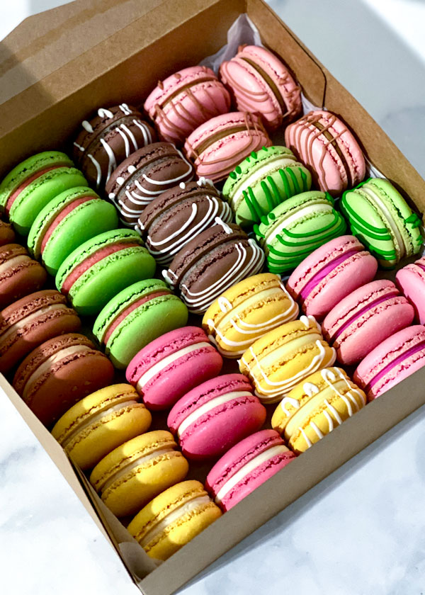 pink, green, yellow and brown macarons in brown box