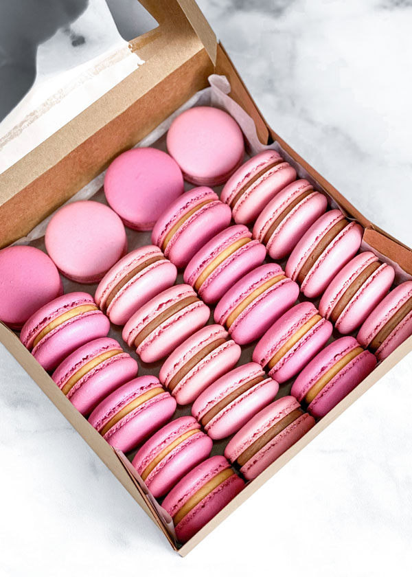 pink french macarons in brown box