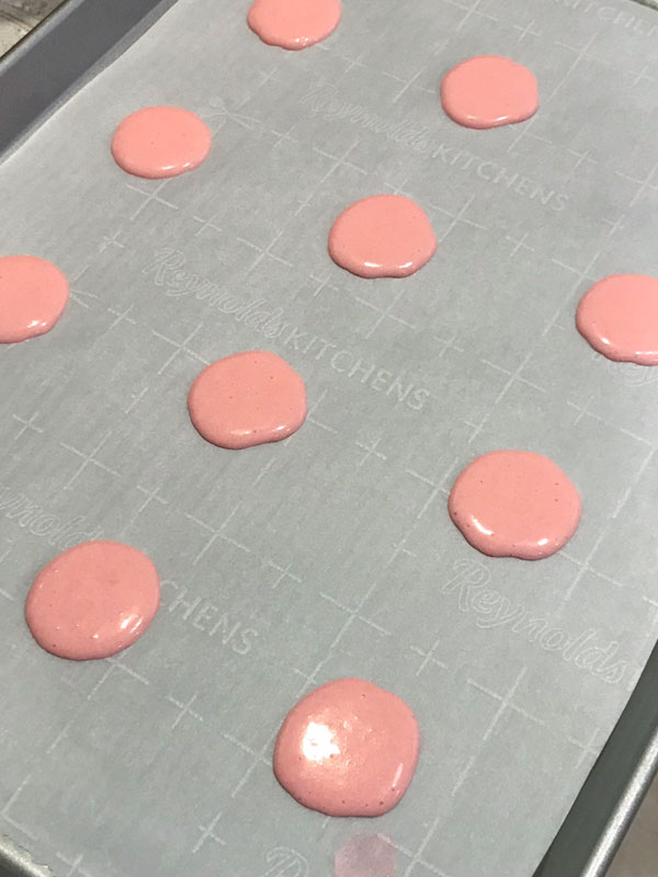 unbaked pink macarons on parchment paper