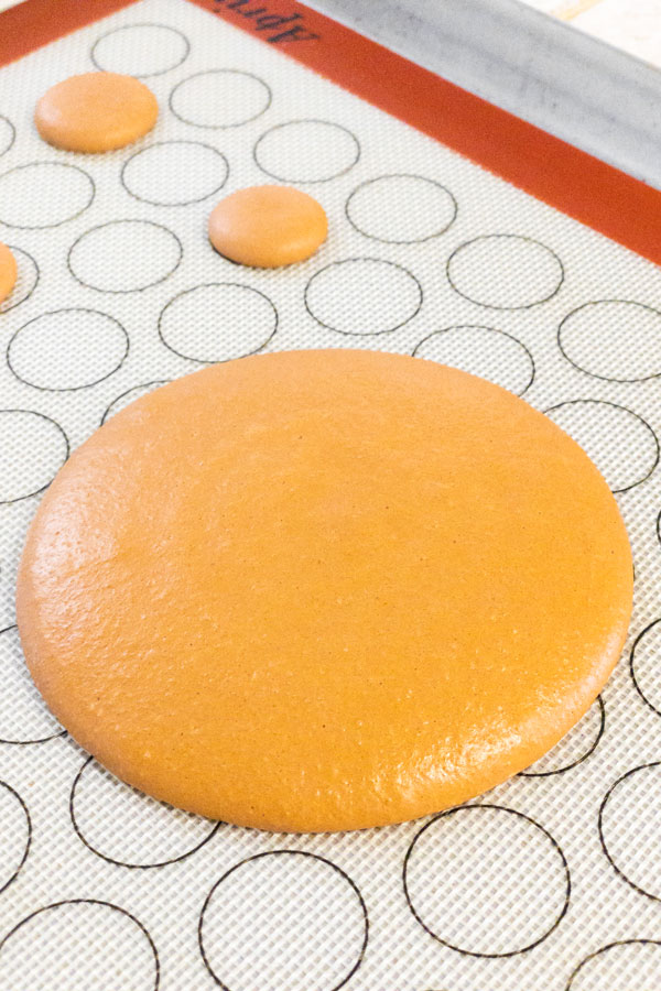 large brown macaron shell on silicone mat
