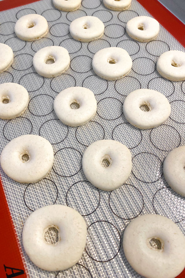 donut shaped macarons piped on silicone mat