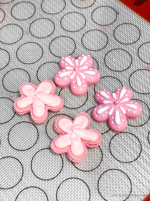 pink flower shaped macarons with pink filling on silicone mat