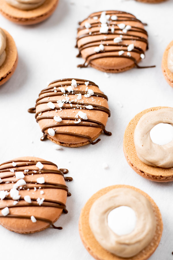 chocolate macarons shells on parchment paper with chocolate and marshmallow filling