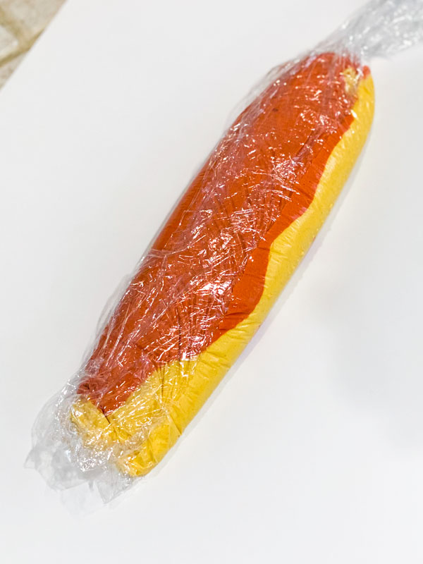yellow and orange peach macaron batter inside plastic wrap