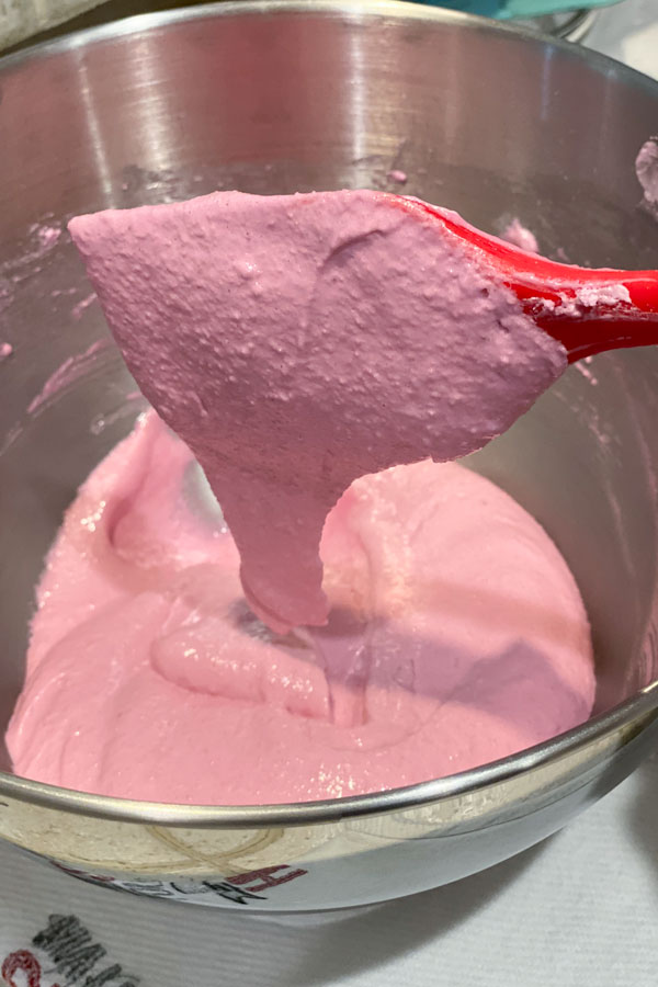 red spatula and pink macaron batter in mixing bowl