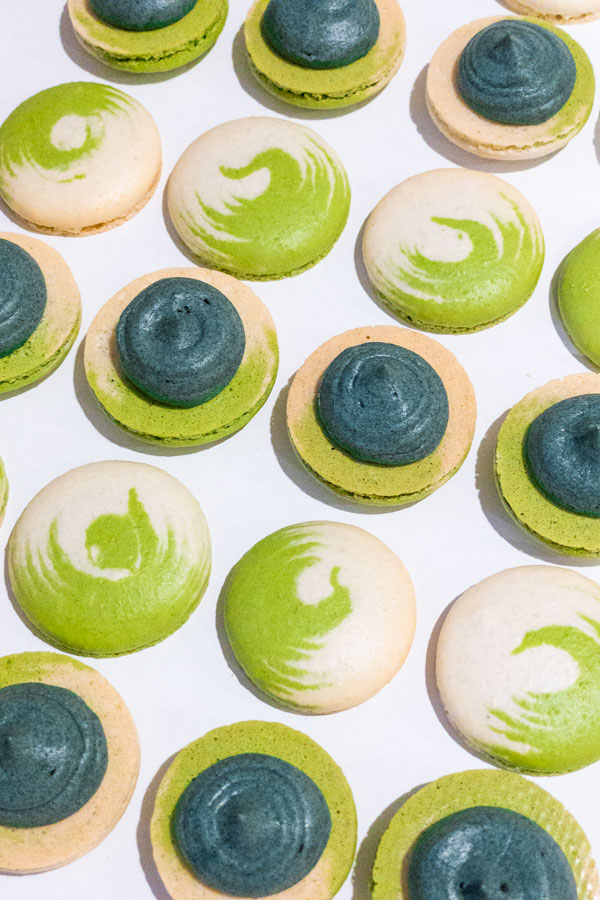 green and white swirled matcha macaron shells with dark green buttercream