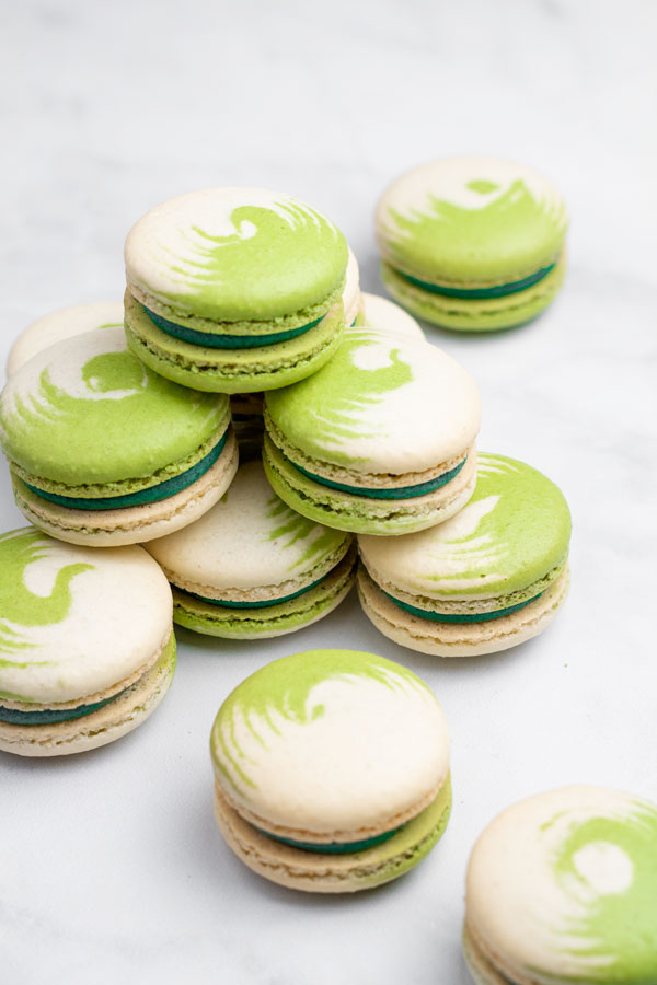 green and white swirled matcha macarons on top of other macarons