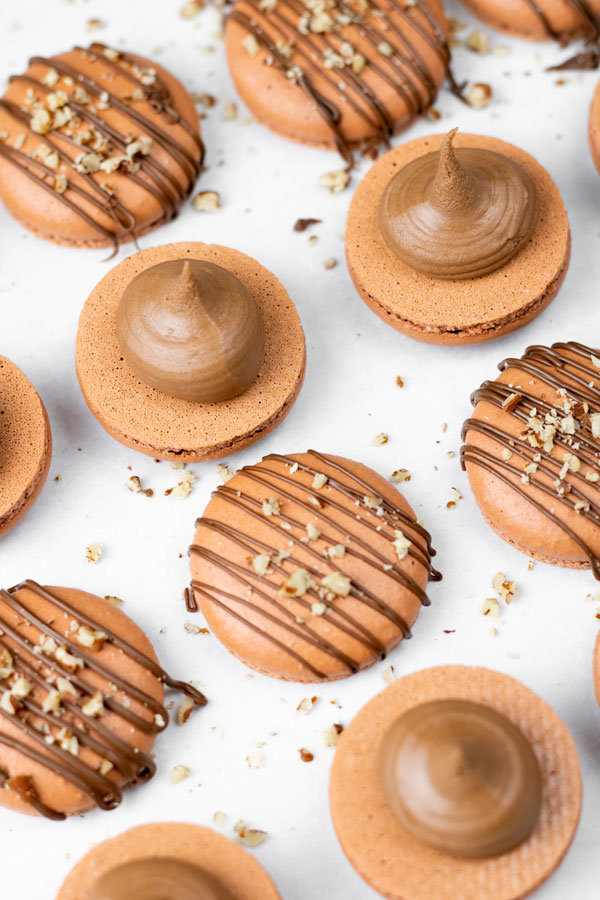 brown macaron shells filled with nutella buttercream and drizzled with chocolate