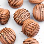 brown macarons filled with nutella buttercream and drizzled with chocolate and hazelnuts