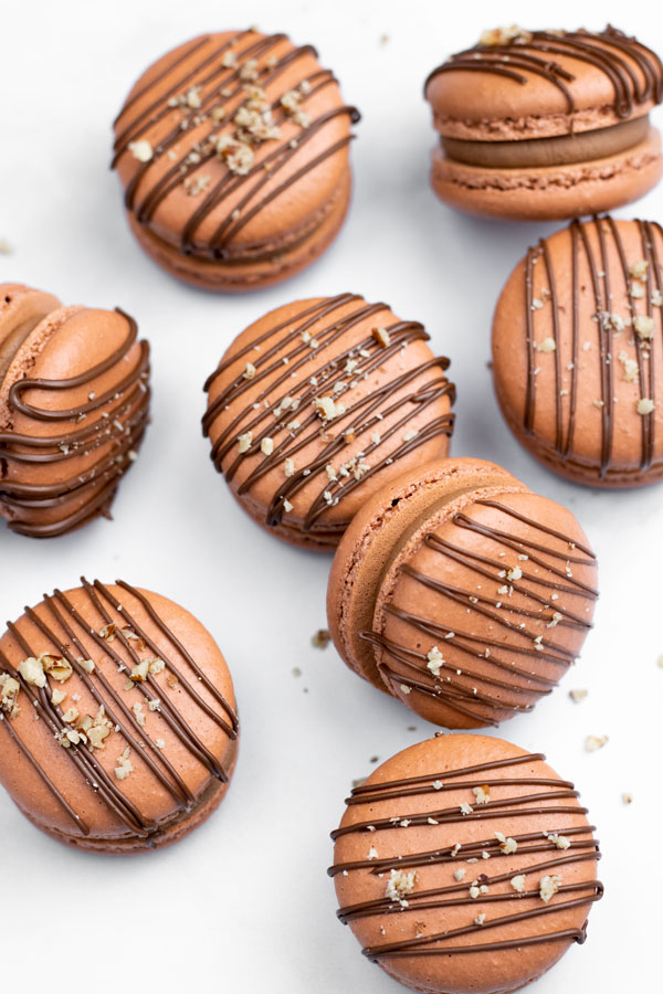 brown macarons filled with nutella buttercream and drizzled with chocolate and hazelnuts