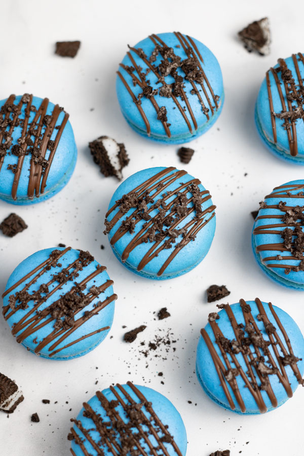 blue oreo macarons with chocolate drizzle and crushed oreo cookies