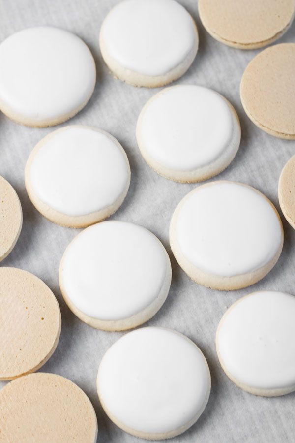 white macaron shells with white royal icing