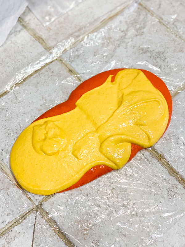yellow and orange peach macaron batter poured on plastic wrap