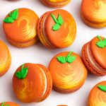 orange and yellow peach macarons with green leaf icing decoration