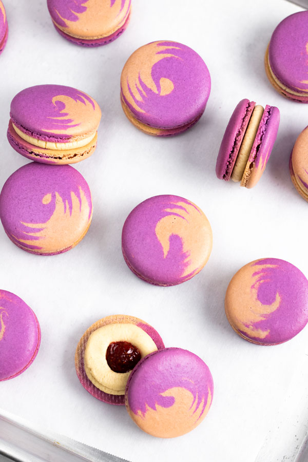 purple and brown peanut butter and jelly macarons with peanut butter buttercream