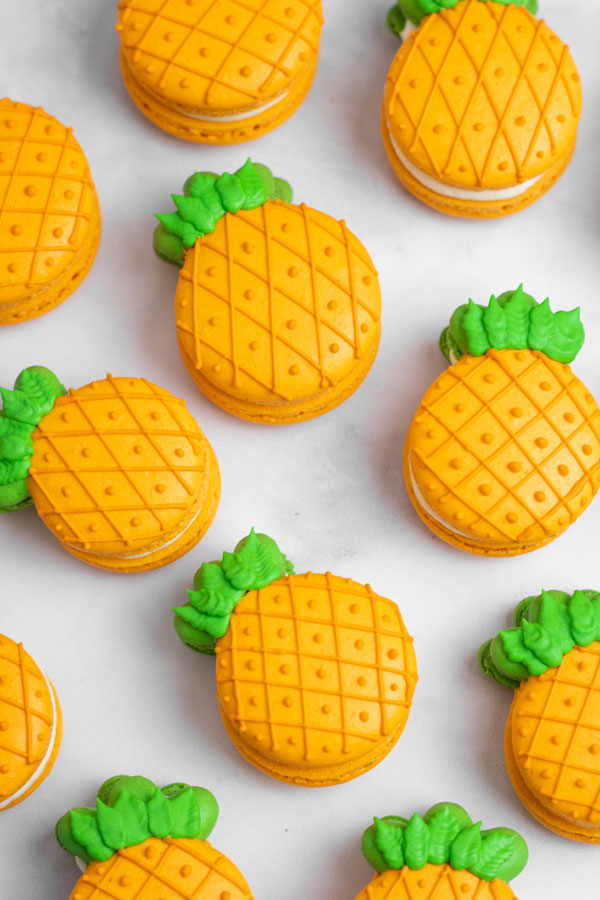 orange and green pineapple macarons on white background