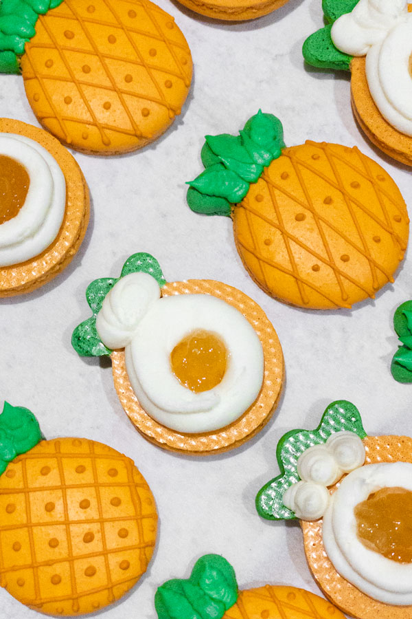 orange and green pineapple shaped macaron shells with filling