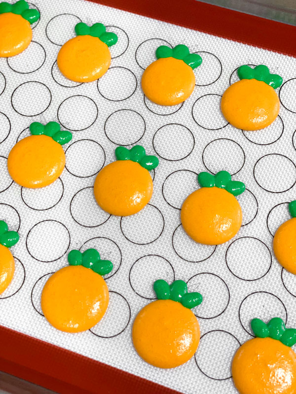 orange and green unbaked pineapple macaron shells silicone mat